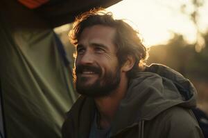 portrait de homme à la recherche à caméra tandis que près camping tente à le coucher du soleil ai généré photo