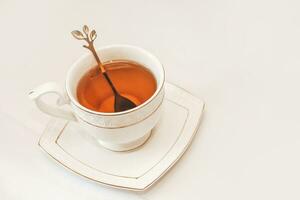 blanc tasse avec soucoupe et d'or cuillère et thé feuilles photo