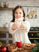 enfant souriant et en portant deux bonbons cannes dans forme de cœur dans moderne cuisine photo