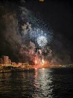 coloré feux d'artifice dans le nuit ciel sur le front de mer de alicante Espagne photo