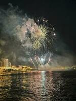 coloré feux d'artifice dans le nuit ciel sur le front de mer de alicante Espagne photo