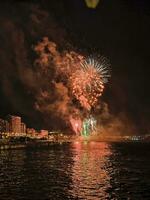 coloré feux d'artifice dans le nuit ciel sur le front de mer de alicante Espagne photo