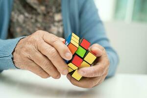 Bangkok, Thaïlande août 14, 2023 Alzheimer maladie publicité, asiatique personnes âgées femme patient en jouant Rubik cube Jeu à entraine toi cerveau formation pour démence la prévention. photo