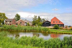 une petit étang avec Maisons et une pont photo