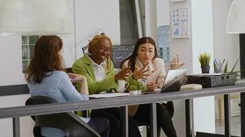 diverse équipe de collègues de travail Faire collaboration dans Bureau à plan annuel rapport, vérification en ligne analytique sur des dossiers dans cotravail espace. femelle ouvriers discuter entreprise croissance. trépied tir. photo