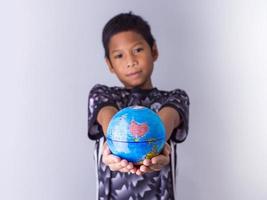 garçon tenant un globe se démarquer devant. photo