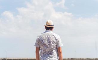 vue arrière d'un homme en chemise et chapeau d'été regardant le ciel photo