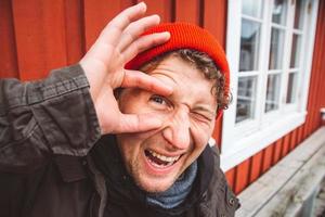 L'homme de voyageur de portrait s'assied près de la maison de couleur rouge en bois photo