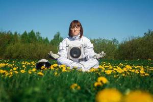 Une femme astronaute sans casque est assise sur une pelouse verte parmi les fleurs photo