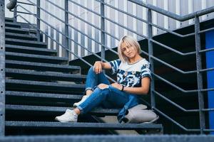 femme aux cheveux blancs courts dans un style urbain est assise sur les escaliers métalliques photo