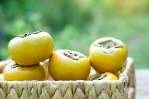 mûr Jaune sucré kaki des fruits dans osier panier. diospyros famille les plantes. concept, agriculture cultures. saisonnier fruit. en bonne santé alimentaire. photo