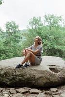 femme assise sur un gros rocher dans la forêt, se reposant ou méditant