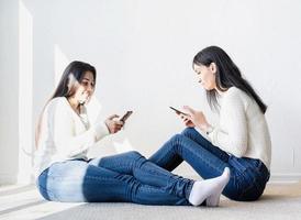 deux belles amies envoyant des messages avec des téléphones portables photo