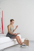 jeune femme faisant du shopping en ligne assise à la maison sur le lit photo