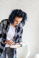 femme créative avec la peinture de cheveux teints en bleu dans son studio photo