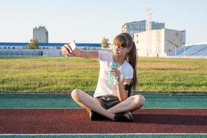 adolescente faisant selfie au stade après l'entraînement de l'eau potable photo