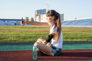 adolescente faisant selfie au stade après l'entraînement de l'eau potable photo