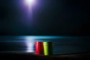 deux seaux asseoir sur le plage à nuit. généré par ai photo