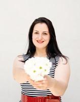 jeune femme tenant un bouquet de fleurs sur un fond uni gris photo