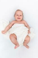 mignonne content bébé mensonges sur une blanc feuille et est couvert avec une de laine tissu photo
