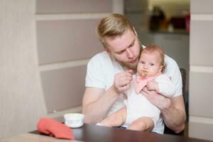 père alimentation le sien enfant avec fruit purée de une cuillère photo