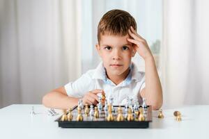 intelligent garçon apprend à jouer échecs par lui-même dans le sien pièce à Accueil photo