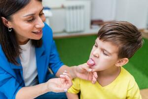 une femme discours thérapeute offres avec le enfant et enseigne lui le correct prononciation et compétent discours. photo