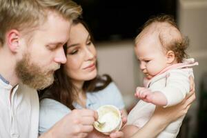 Parents alimentation leur fille fruit purée ensemble dans le cuisine photo