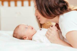 portrait de une Jeune femme qui tendrement se soucie pour sa bébé photo