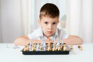 intelligent garçon apprend à jouer échecs par lui-même dans le sien pièce à Accueil photo