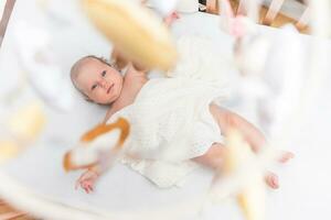 portrait de une magnifique bébé fille mensonges sur une blanc feuille dans sa pièce photo