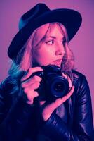 portrait de une magnifique fille photographe dans une chapeau qui prend des photos dans le studio sur une fiolet Contexte