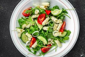 Pâtes salade fusilli Pâtes, concombre, tomate, vert laitue, oignon en mangeant apéritif repas nourriture casse-croûte sur le table copie espace nourriture Contexte rustique Haut vue photo