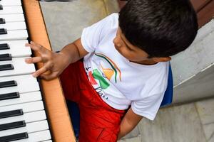 asiatique garçon en jouant le synthétiseur ou piano. mignonne peu enfant apprentissage Comment à jouer piano. enfant mains sur le clavier intérieur. photo