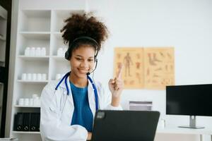 femelle médecin séance sur travail bureau médical en ligne, e santé concept. médecin en utilisant portable pour travail, vidéo appel vidéo bavarder avec collègues. photo