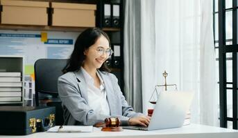 Justice et loi concept. asiatique femelle juge dans une salle d'audience sur en bois table et conseiller ou Masculin avocat travail dans moderne bureau. photo