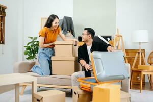 Jeune couple avec gros des boites en mouvement dans une Nouveau loger, Nouveau appartement pour couple, Jeune homme et femme portion à ascenseur des boites sur canapé pour le Nouveau maison, en mouvement maison. photo