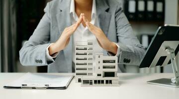 agent immobilier féminin utilise les mains pour protéger le toit rouge pour le concept d'investissement immobilier sur le commerce de la maison, achat au bureau au bureau photo