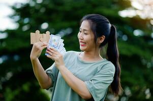 dollar dans le mains de un asiatique femme des économies, investissements, salaire, revenu, en espèces couler, bonheur et financier Succès et investissements. photo