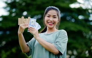 dollar dans le mains de un asiatique femme des économies, investissements, salaire, revenu, en espèces couler, bonheur et financier Succès et investissements. photo