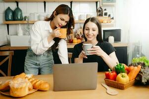deux élèves apprentissage ensemble en ligne avec une ordinateur portable, tablette et tuteur ensemble dans le cuisine ou vivant pièce à maison. photo