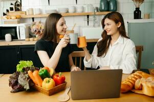 deux élèves apprentissage ensemble en ligne avec une ordinateur portable, tablette et tuteur ensemble dans le cuisine ou vivant pièce à maison. photo