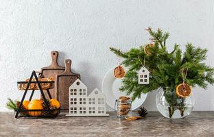 épicéa branches dans une blanc cruche décoré avec sec Orange tranches et une élégant panier de Frais des oranges des fruits sur le Nouveau années comptoir. photo