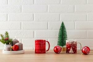 rouge des tasses avec Noël modèle, bougie ensemble, rouge Balle et décoratif Noël arbre sur cuisine comptoir. de fête cuisine Contexte. minimalisme. photo