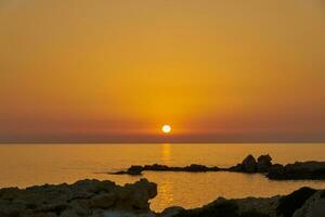 le pierre côte de le méditerranéen mer à le coucher du soleil. photo