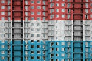 Luxembourg drapeau représenté dans peindre couleurs sur à plusieurs étages résidentielle bâtiment en dessous de construction. texturé bannière sur brique mur Contexte photo