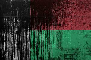 Madagascar drapeau représenté dans peindre couleurs sur vieux et sale pétrole baril mur fermer. texturé bannière sur rugueux Contexte photo