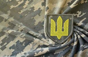 symbole de ukrainien armée sur le camouflage uniforme de une ukrainien soldat. le concept de guerre dans Ukraine, patriotisme et protéger votre pays de occupants photo