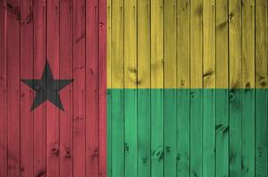Guinée Bissau drapeau représenté dans brillant peindre couleurs sur vieux en bois mur. texturé bannière sur rugueux Contexte photo