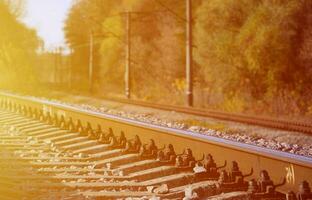 paysage industriel d'automne. chemin de fer reculant au loin parmi les arbres d'automne verts et jaunes photo